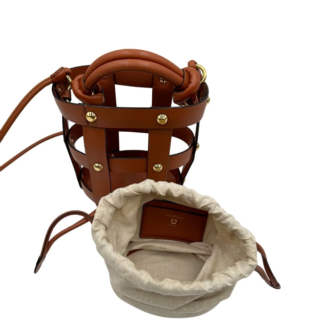 Borsa a secchiello Salvatore Ferragamo in pelle marrone cognac con sacca interna in tela beige con chiusura a coulisse. Munita di un manico stondato e tracolla, parti metalliche dorate. Completa di dustbag. Originale, usato, in condizioni ottime. 