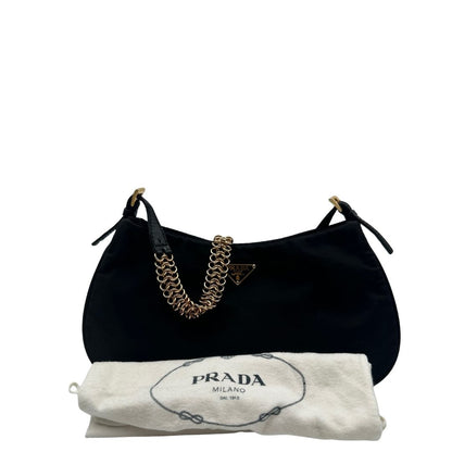 Borsa Prada in nylon nero con parti metalliche dorate e finiture in pelle tono su tono. Munta di un manico in catena leggermente regolabile con fibbie, e rifinita con classico logo triangolare sul front. Completa di dustbag. Originale, usato, in condizioni ottime. 