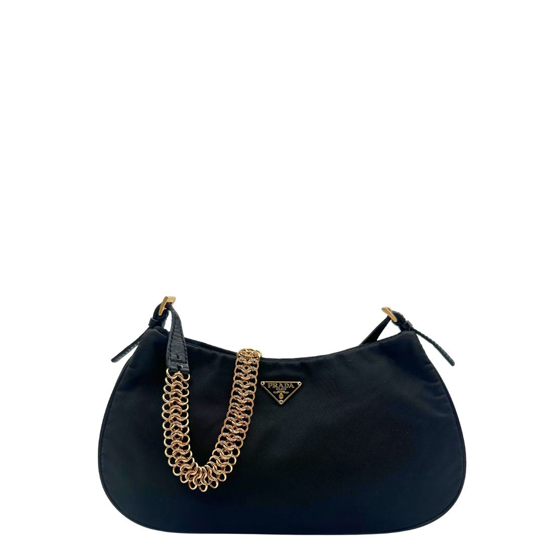 Borsa Prada in nylon nero con parti metalliche dorate e finiture in pelle tono su tono. Munta di un manico in catena leggermente regolabile con fibbie, e rifinita con classico logo triangolare sul front. Completa di dustbag. Originale, usato, in condizioni ottime. 