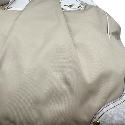 Borsa Tote Prada in nylon bianco panna con finiture in pelle bianco gesso e parti metalliche dorate. Munita di doppi manici stondati con tag porta address rimovibile. Rifinita con logo lettering al di sotto del manico. Originale, usato, in condizioni ottime. 