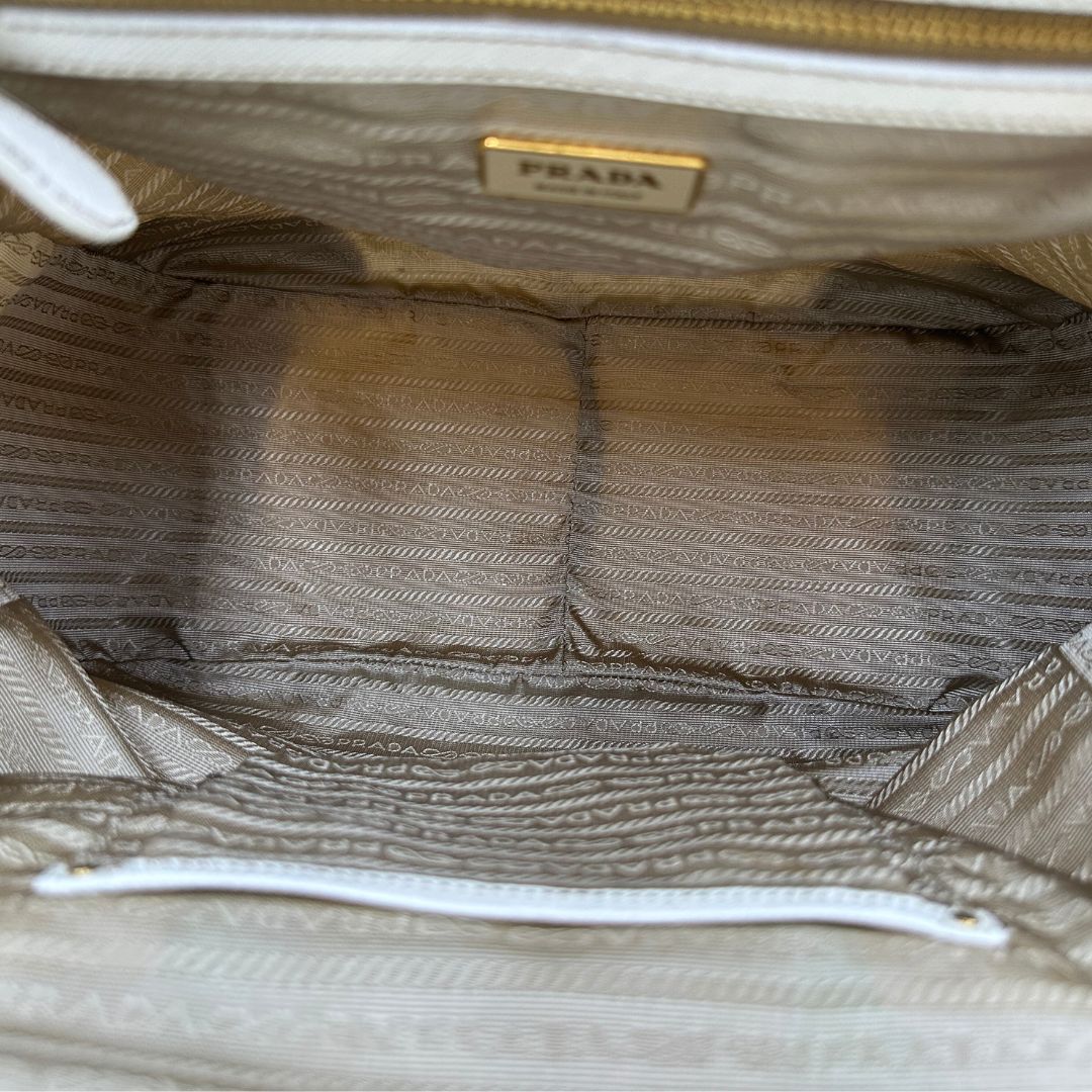 Interno Borsa Tote Prada in nylon bianco panna con finiture in pelle bianco gesso e parti metalliche dorate. Munita di doppi manici stondati con tag porta address rimovibile. Rifinita con logo lettering al di sotto del manico. Originale, usato, in condizioni ottime. 
