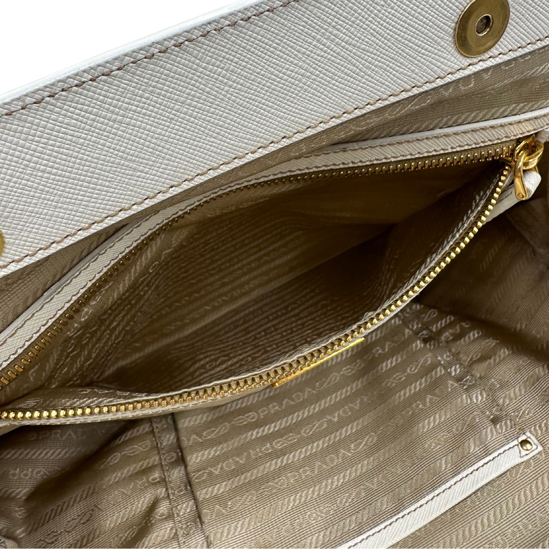 Interno Borsa Tote Prada in nylon bianco panna con finiture in pelle bianco gesso e parti metalliche dorate. Munita di doppi manici stondati con tag porta address rimovibile. Rifinita con logo lettering al di sotto del manico. Originale, usato, in condizioni ottime. 