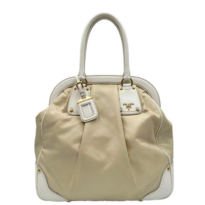 Borsa Tote Prada in nylon bianco panna con finiture in pelle bianco gesso e parti metalliche dorate. Munita di doppi manici stondati con tag porta address rimovibile. Rifinita con logo lettering al di sotto del manico. Originale, usato, in condizioni ottime. 