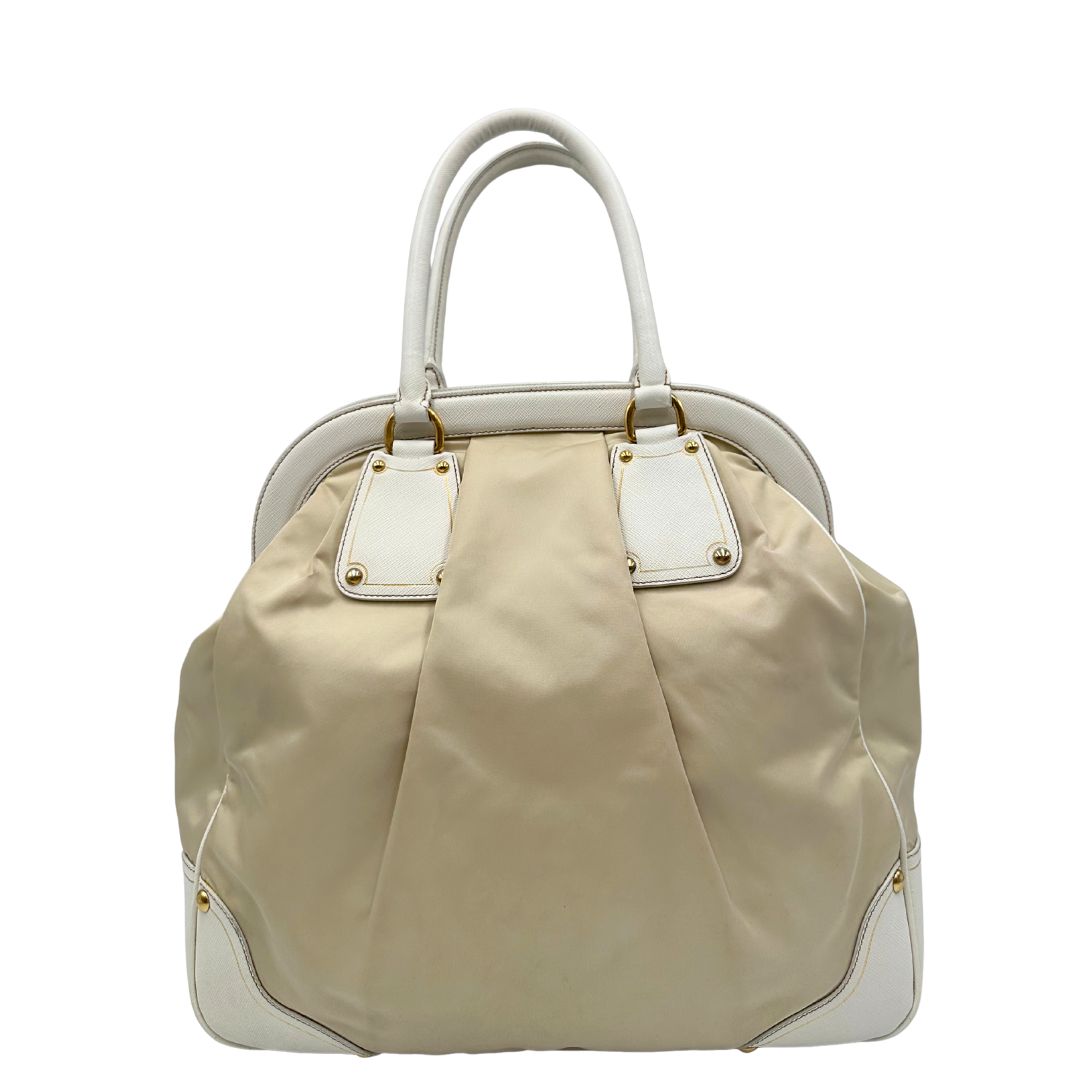 Retro Borsa Tote Prada in nylon bianco panna con finiture in pelle bianco gesso e parti metalliche dorate. Munita di doppi manici stondati con tag porta address rimovibile. Rifinita con logo lettering al di sotto del manico. Originale, usato, in condizioni ottime. 