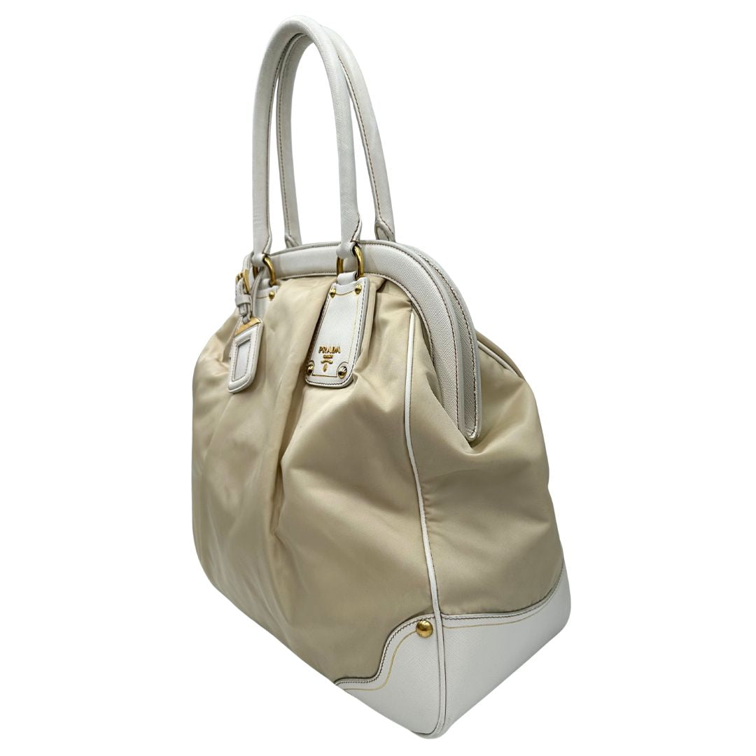 Laterale Borsa Tote Prada in nylon bianco panna con finiture in pelle bianco gesso e parti metalliche dorate. Munita di doppi manici stondati con tag porta address rimovibile. Rifinita con logo lettering al di sotto del manico. Originale, usato, in condizioni ottime. 