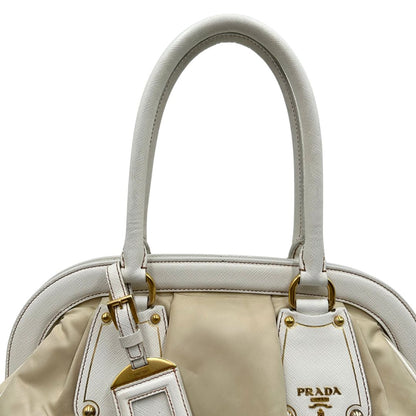 Borsa Tote Prada in nylon bianco panna con finiture in pelle bianco gesso e parti metalliche dorate. Munita di doppi manici stondati con tag porta address rimovibile. Rifinita con logo lettering al di sotto del manico. Originale, usato, in condizioni ottime. 