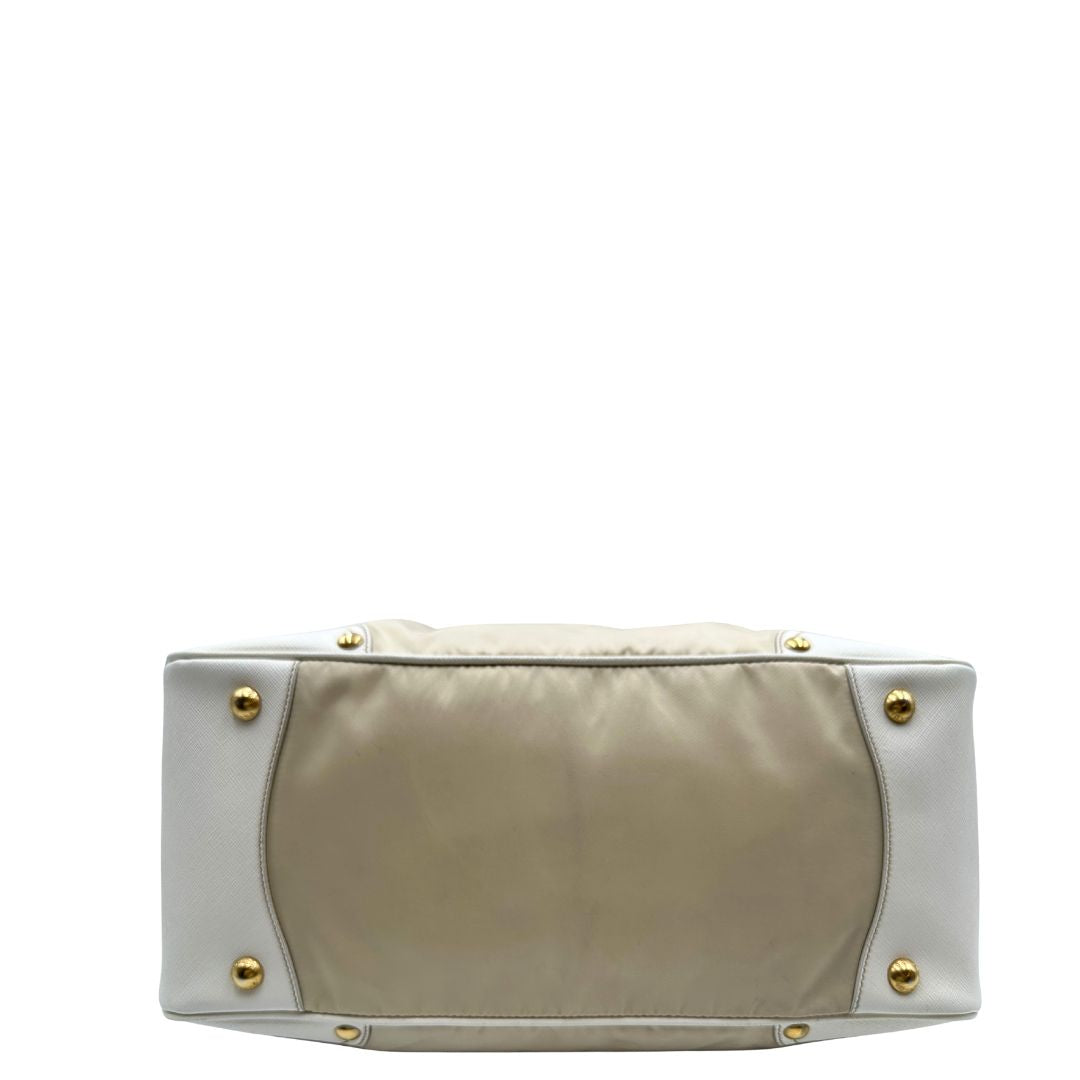 Base Borsa Tote Prada in nylon bianco panna con finiture in pelle bianco gesso e parti metalliche dorate. Munita di doppi manici stondati con tag porta address rimovibile. Rifinita con logo lettering al di sotto del manico. Originale, usato, in condizioni ottime. 