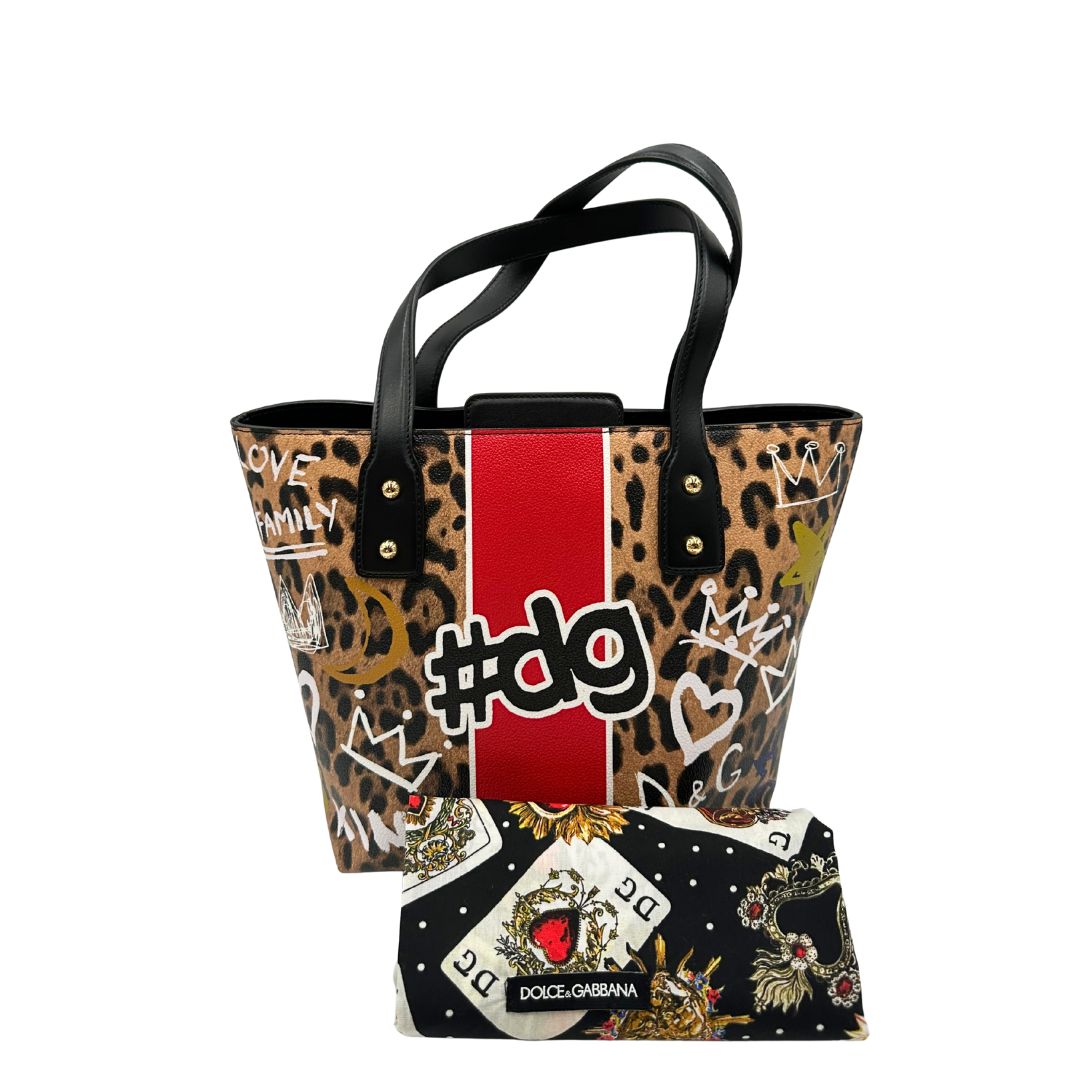 Borsa D&G tote Beatrice in canvas con motivo animalier e dettagli graffiti in stile street-art. Il design è arricchito da scritte, cuori e corone, e impreziosita da una striscia centrale rossa. Presenta doppi manici in pelle nera e parti metalliche dorate. Completa di dustbag, cartellino e card d'autenticità. Originale, usato, in condizioni ottime. 