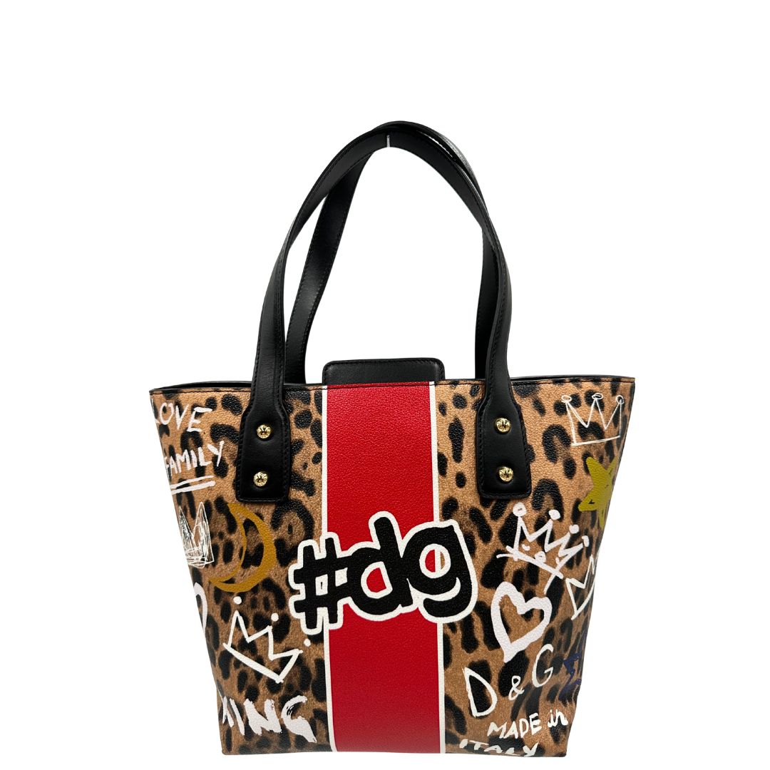 Borsa D&G tote Beatrice in canvas con motivo animalier e dettagli graffiti in stile street-art. Il design è arricchito da scritte, cuori e corone, e impreziosita da una striscia centrale rossa. Presenta doppi manici in pelle nera e parti metalliche dorate. Completa di dustbag, cartellino e card d'autenticità. Originale, usato, in condizioni ottime. 