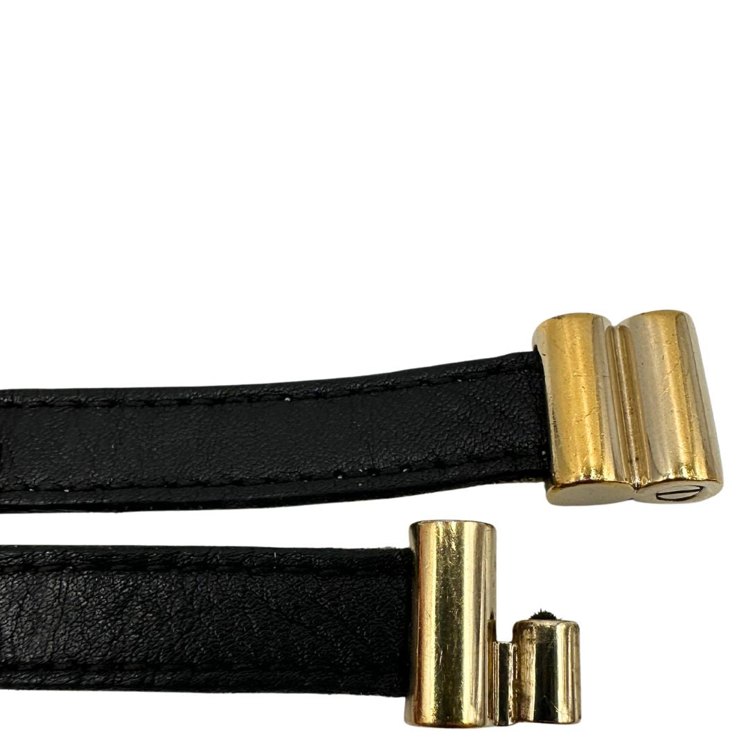 Chiusura di un bracciale Bulgari in pelle nero a doppio giro, con charm in metallo dorati. Completo di scatola logata.