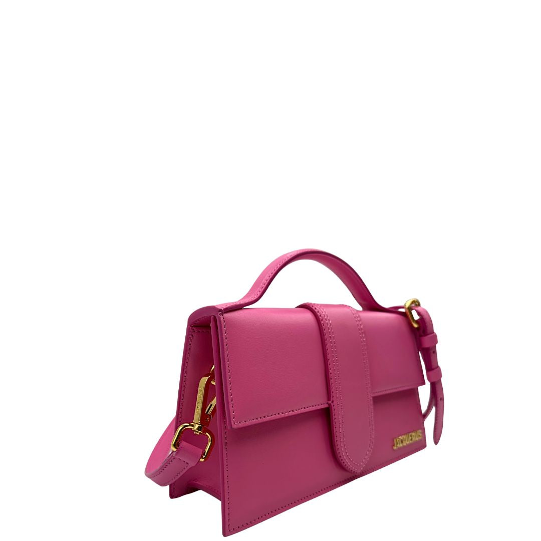 Laterale Le Grand Bambino Jacquemus in pelle neon pink con parti metalliche dorate; da portare a mano o a tracolla. Completa di dustbag. Originale, usato, in condizioni ottime. 