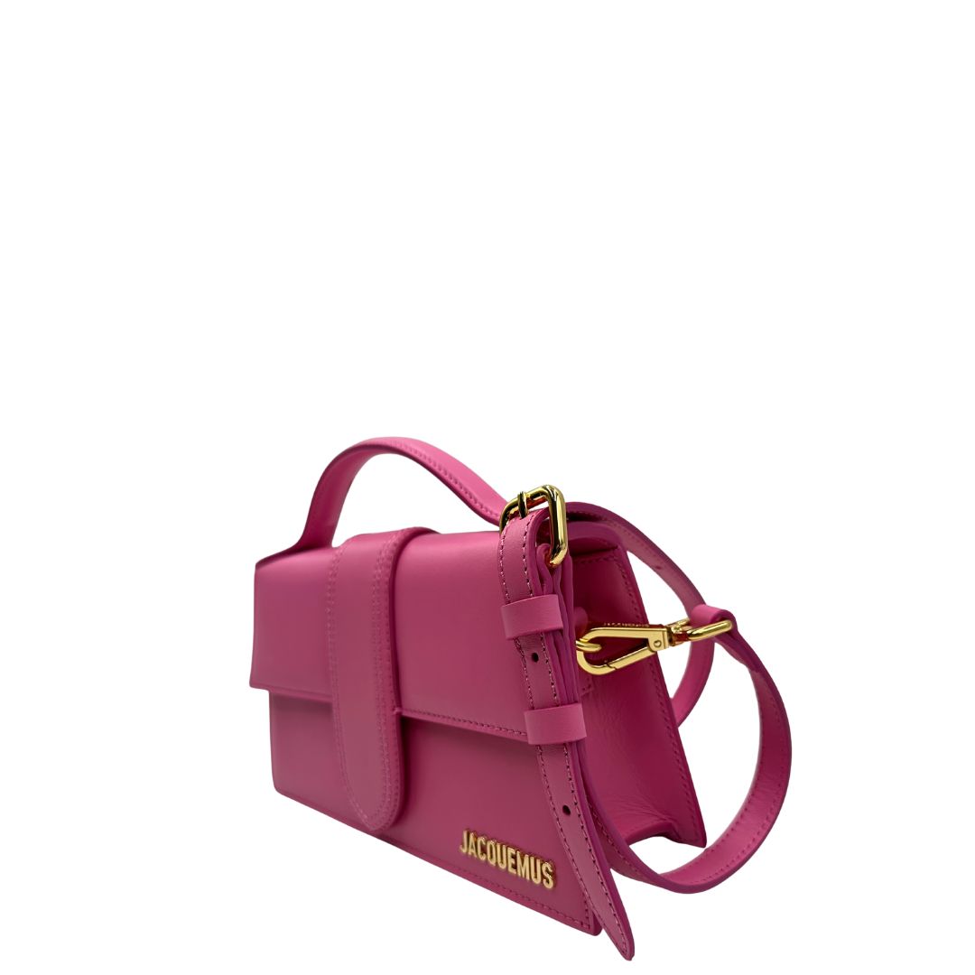 Laterale Le Grand Bambino Jacquemus in pelle neon pink con parti metalliche dorate; da portare a mano o a tracolla. Completa di dustbag. Originale, usato, in condizioni ottime. 