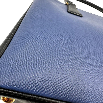 Borsa Prada in pelle saffiano blu e nera con parti metalliche dorate; munita di doppi manici stondati e impreziosita da un portachiavi. Completa di dustbag, di lusso, originale, ottime condizoni, usata. 