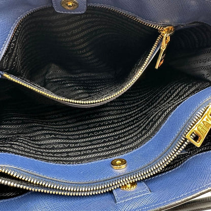 interno Borsa Prada in pelle saffiano blu e nera con parti metalliche dorate; munita di doppi manici stondati e impreziosita da un portachiavi. Completa di dustbag, di lusso, originale, ottime condizoni, usata. 