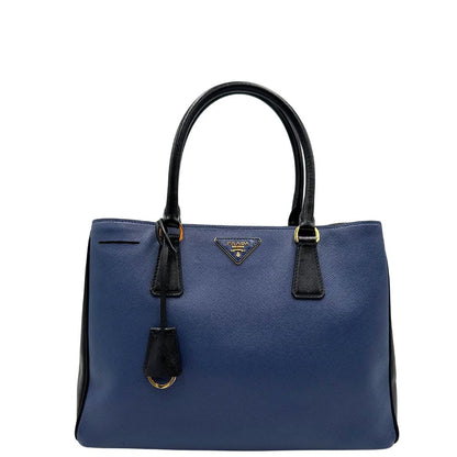 front Borsa Prada in pelle saffiano blu e nera con parti metalliche dorate; munita di doppi manici stondati e impreziosita da un portachiavi. Completa di dustbag, di lusso, originale, ottime condizoni, usata. 