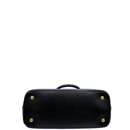 base Borsa Prada in pelle saffiano blu e nera con parti metalliche dorate; munita di doppi manici stondati e impreziosita da un portachiavi. Completa di dustbag, di lusso, originale, ottime condizoni, usata. 