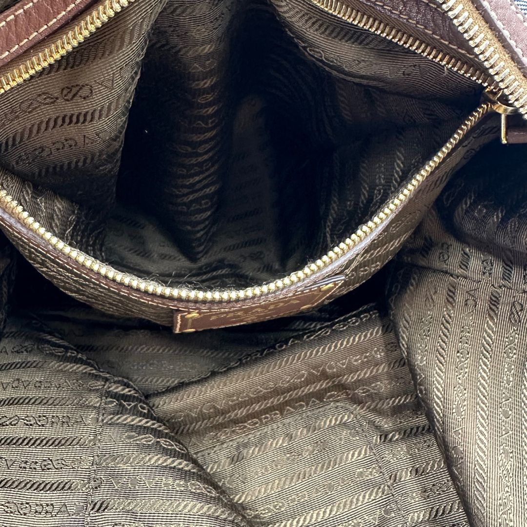 interno Borsa Prada in denim con finiture in pelle marroni e parti metalliche dorate; munita di doppi manici e una tracolla amovibile e regolabile, impreziosita da un porta address. Completa di dustbag, di lusso, ottime condizioni, originale.