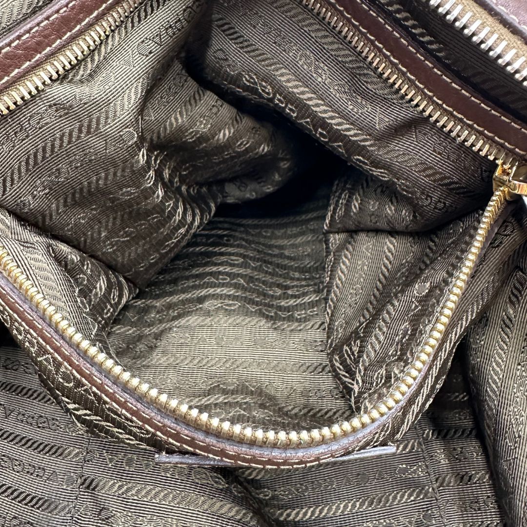 interno Borsa Prada in denim con finiture in pelle marroni e parti metalliche dorate; munita di doppi manici e una tracolla amovibile e regolabile, impreziosita da un porta address. Completa di dustbag, di lusso, ottime condizioni, originale.