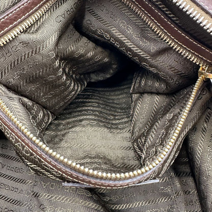 interno Borsa Prada in denim con finiture in pelle marroni e parti metalliche dorate; munita di doppi manici e una tracolla amovibile e regolabile, impreziosita da un porta address. Completa di dustbag, di lusso, ottime condizioni, originale.