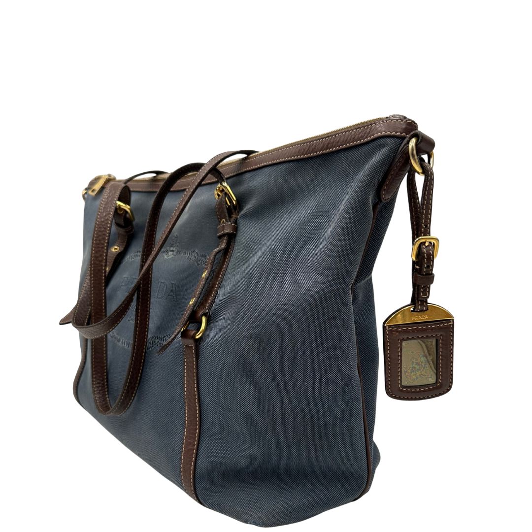 lato Borsa Prada in denim con finiture in pelle marroni e parti metalliche dorate; munita di doppi manici e una tracolla amovibile e regolabile, impreziosita da un porta address. Completa di dustbag, di lusso, ottime condizioni, originale. 