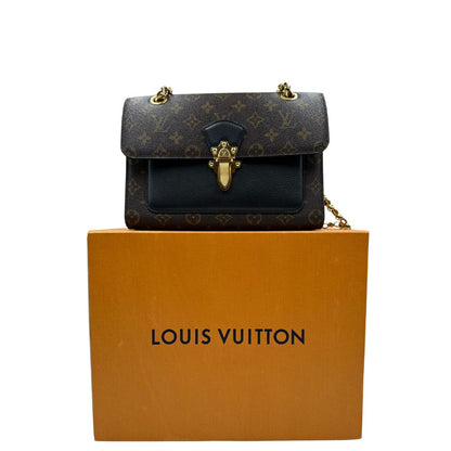 Borsa Louis Vuitton Victoire in canvas marrone monogram, finiture in pelle nera e parti metalliche dorate; munita di una tracolla in catena scorrevole. Completa di scatola, di lusso, originale. 