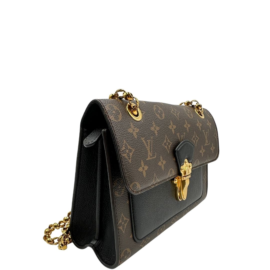 lato Borsa in canvas marrone monogram, finiture nere e parti metalliche dorate; munita di una tracolla in catena scorrevole. Completa di scatola, di lusso, originale, ottime condizioni. 