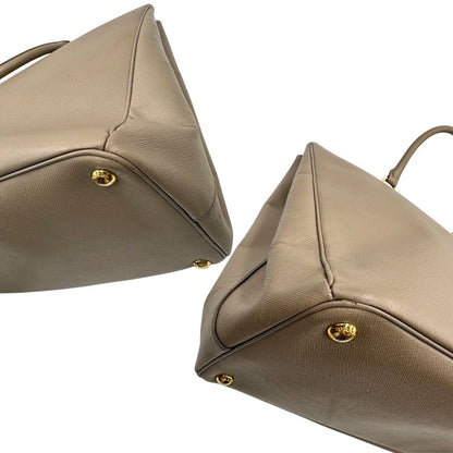 borsa Prada in pelle saffiano color fango con parti metalliche dorate; munita di doppi manici stondati e impreziosita da una clochette portachiavi, di lusso, originale, ottime condizioni.