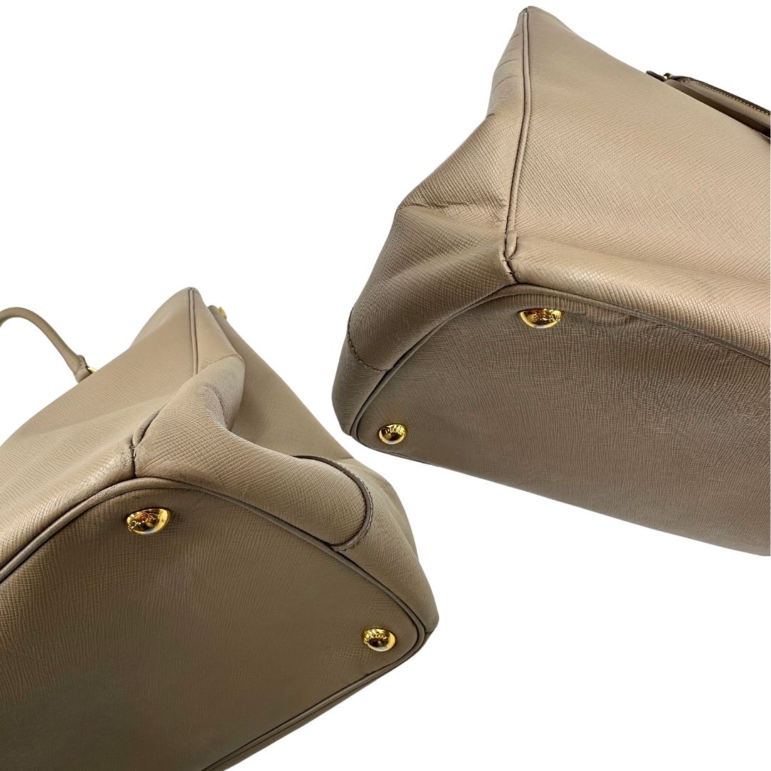 borsa Prada in pelle saffiano color fango con parti metalliche dorate; munita di doppi manici stondati e impreziosita da una clochette portachiavi, di lusso, originale, ottime condizioni.