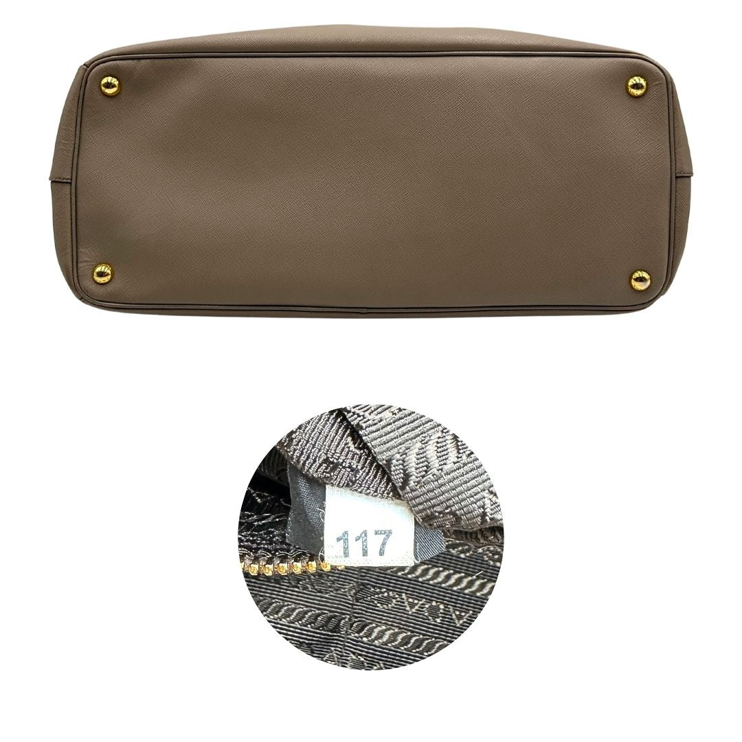 borsa Prada in pelle saffiano color fango con parti metalliche dorate; munita di doppi manici stondati e impreziosita da una clochette portachiavi, di lusso, originale, ottime condizioni.