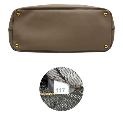 borsa Prada in pelle saffiano color fango con parti metalliche dorate; munita di doppi manici stondati e impreziosita da una clochette portachiavi, di lusso, originale, ottime condizioni.