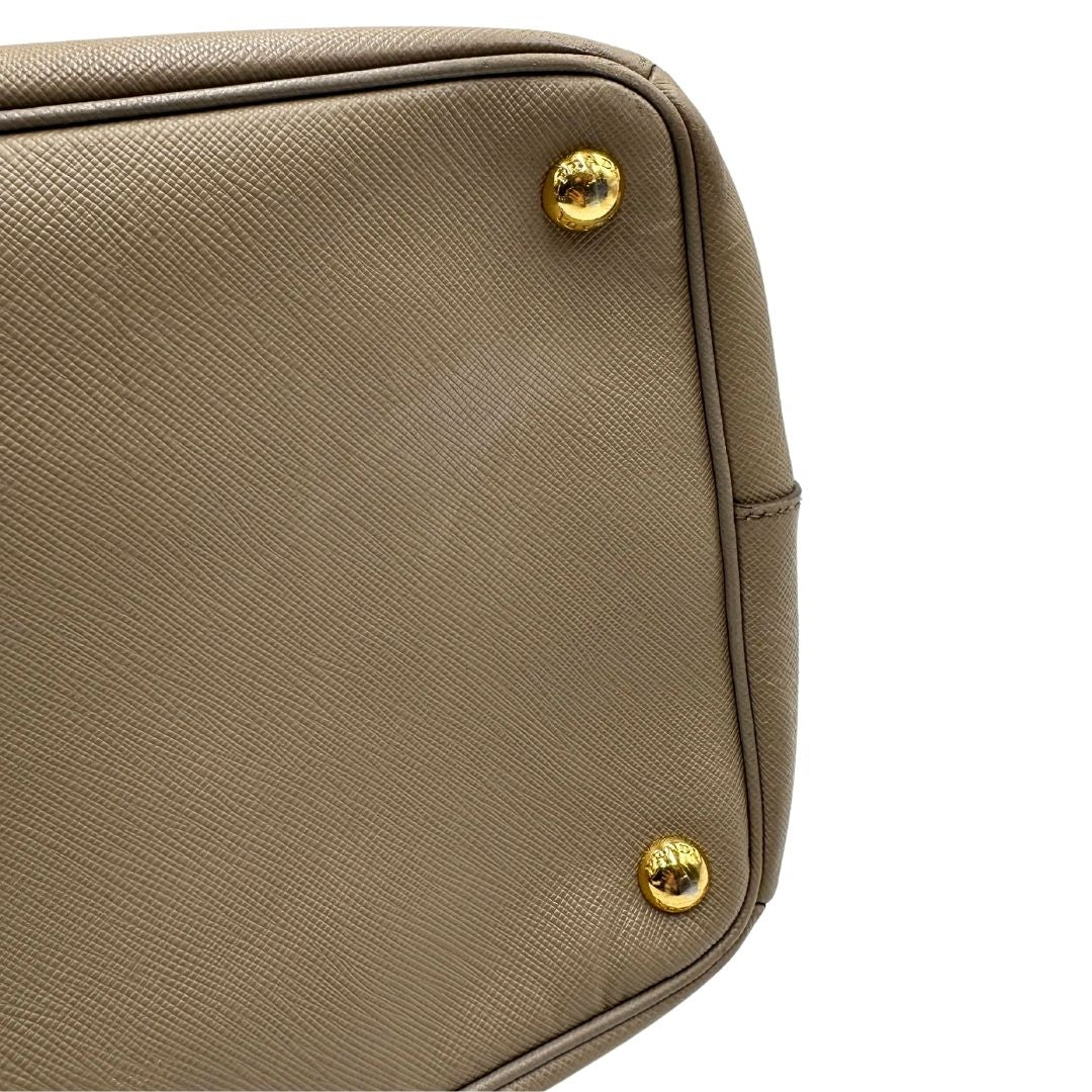 borsa Prada in pelle saffiano color fango con parti metalliche dorate; munita di doppi manici stondati e impreziosita da una clochette portachiavi, di lusso, originale, ottime condizioni.