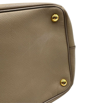 borsa Prada in pelle saffiano color fango con parti metalliche dorate; munita di doppi manici stondati e impreziosita da una clochette portachiavi, di lusso, originale, ottime condizioni.