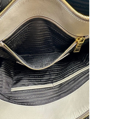 borsa Prada in pelle saffiano color fango con parti metalliche dorate; munita di doppi manici stondati e impreziosita da una clochette portachiavi, di lusso, originale, ottime condizioni.