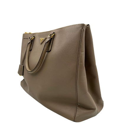 borsa Prada in pelle saffiano color fango con parti metalliche dorate; munita di doppi manici stondati e impreziosita da una clochette portachiavi, di lusso, originale, ottime condizioni.