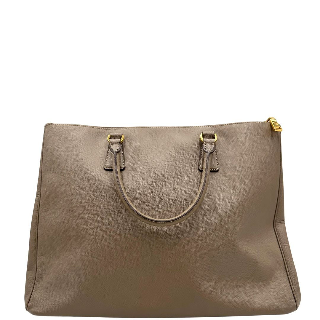 borsa Prada in pelle saffiano color fango con parti metalliche dorate; munita di doppi manici stondati e impreziosita da una clochette portachiavi, di lusso, originale, ottime condizioni.