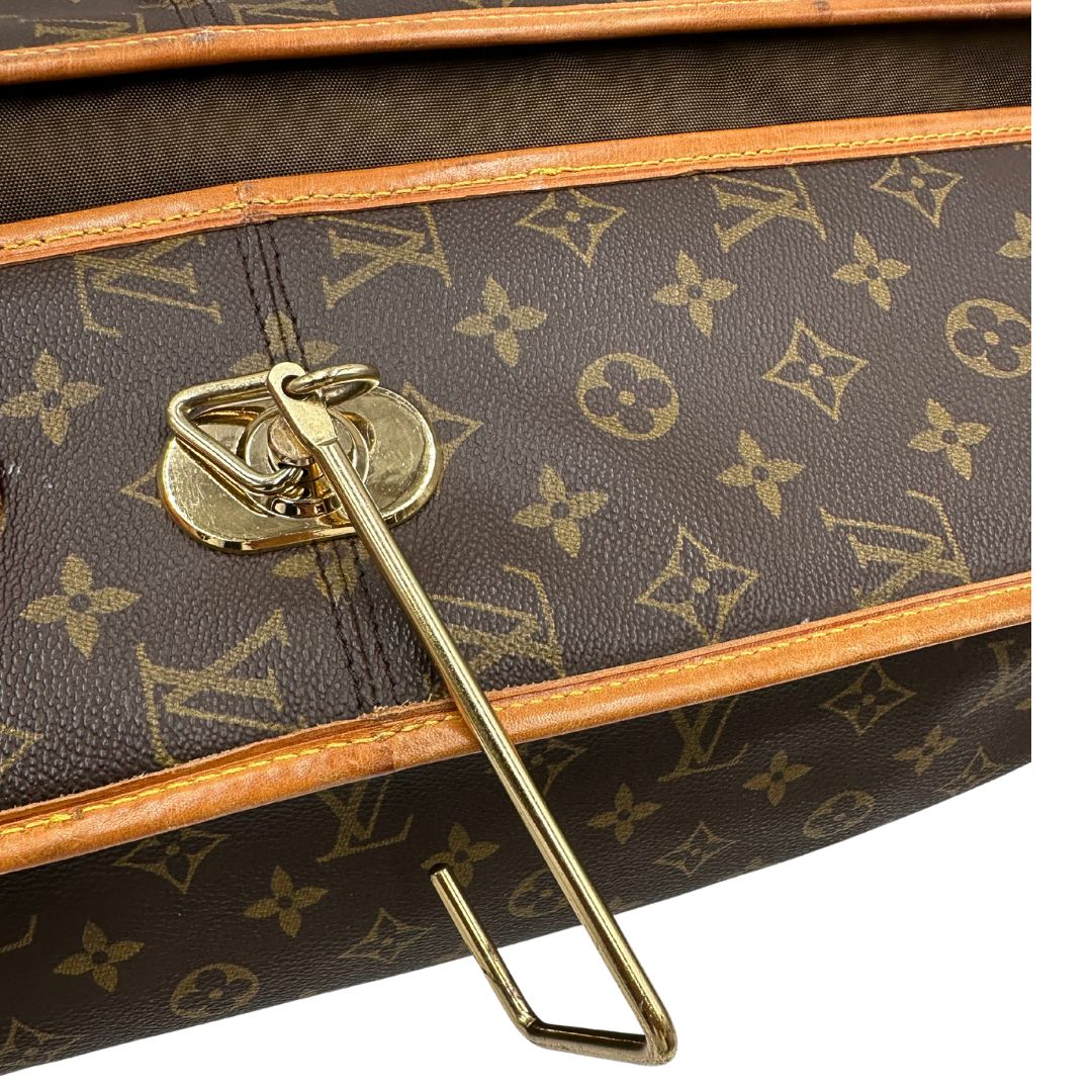 Borsa da viaggio in canvas marrone monogram con finiture in vacchetta naturale e parti metalliche dorate; munita di un manico singolo,una tracolla amovibile e regolabile e 5 grucce, di lusso, originale, ottime condizioni.