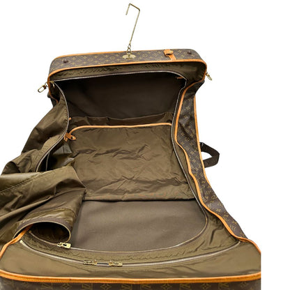 interno Borsa da viaggio in canvas marrone monogram con finiture in vacchetta naturale e parti metalliche dorate; munita di un manico singolo,una tracolla amovibile e regolabile e 5 grucce, di lusso, originale, ottime condizioni. 