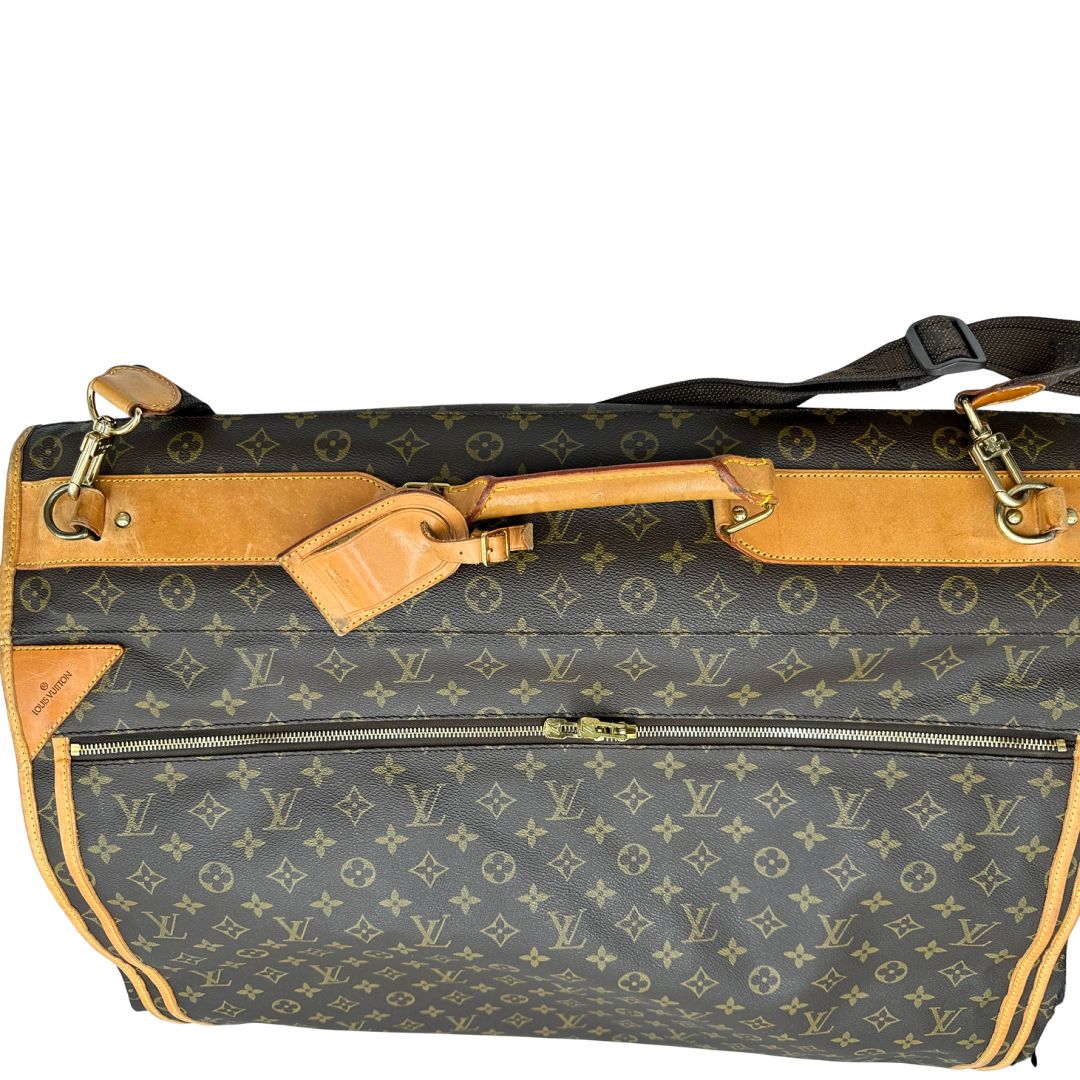 Borsa da viaggio in canvas marrone monogram con finiture in vacchetta naturale e parti metalliche dorate; munita di un manico singolo,una tracolla amovibile e regolabile e 5 grucce, di lusso, originale, ottime condizioni.