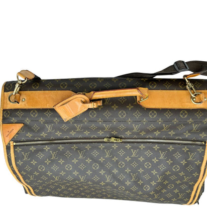 Borsa da viaggio in canvas marrone monogram con finiture in vacchetta naturale e parti metalliche dorate; munita di un manico singolo,una tracolla amovibile e regolabile e 5 grucce, di lusso, originale, ottime condizioni.