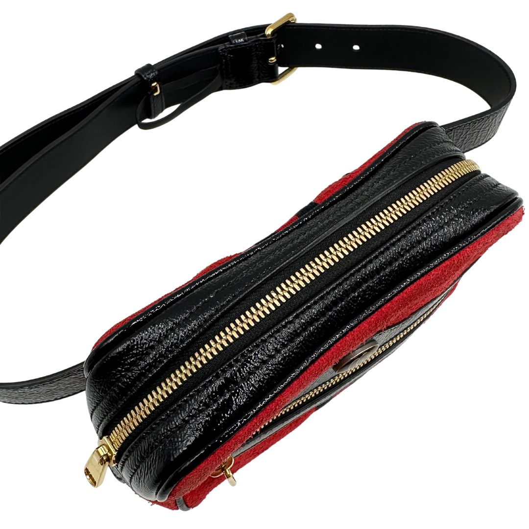 Vista superiore di un marsupio Gucci Ophidia in pelle scamosciata rossa con finiture in pelle verniciata nera, striscia Web centrale in tessuto blu e rosso, cintura regolabile e amovibile, parti metalliche dorate. Completo di dustbag.
