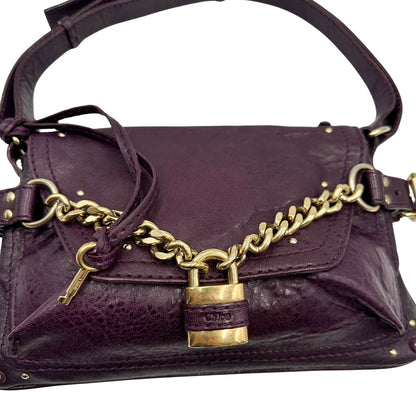 Borsa Chloé Maxi Lock in pelle viola prugna con parti metalliche dorate. Munita di un manico regolabile e impreziosita da una catena sul front con lucchetto. Originale, usato, in condizioni ottime. 