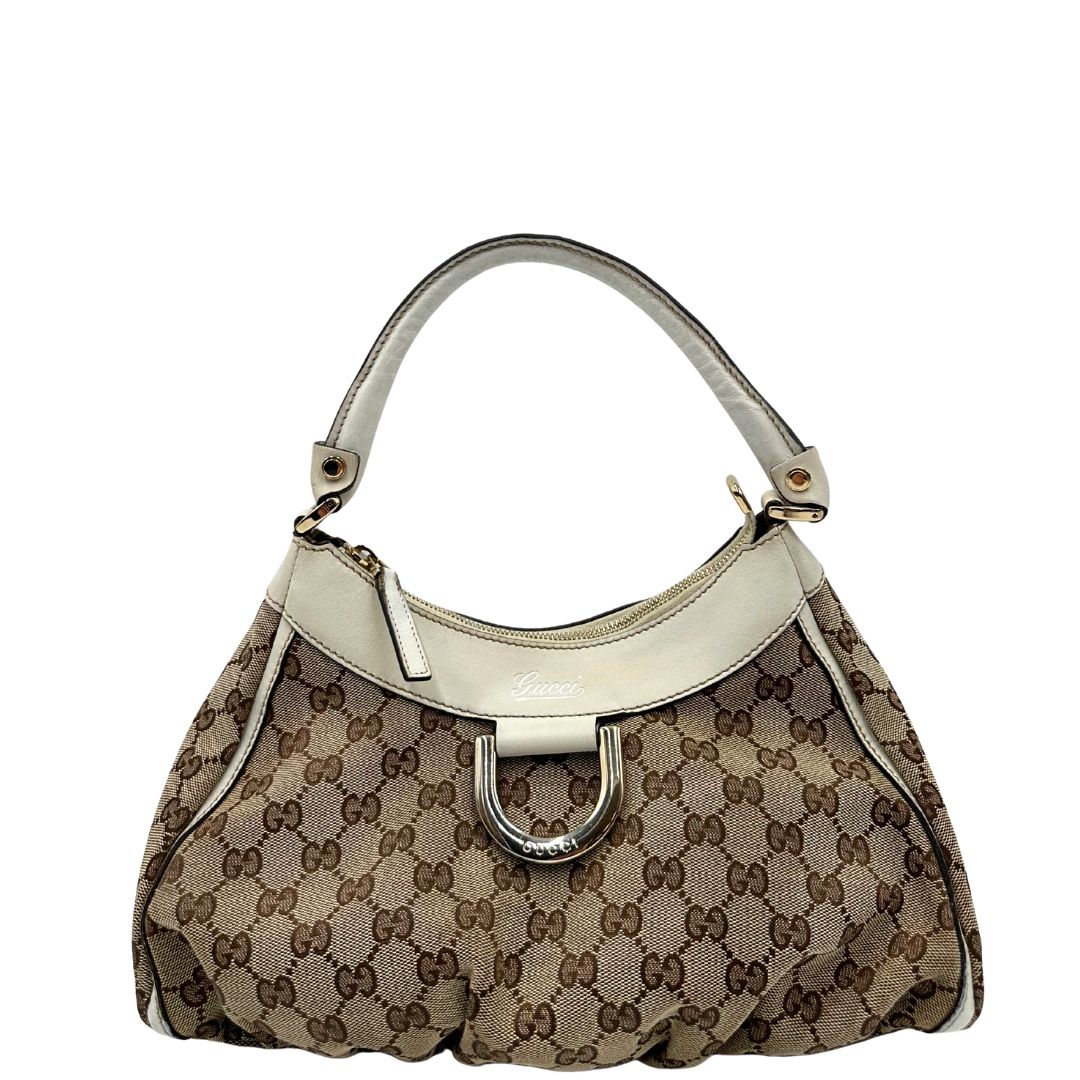Borsa Gucci Hobo D-Ring in tessuto beige GG con finiture in pelle bianca e parti metalliche dorate. Munita di un manico in pelle stondato, rifinita con dettaglio D-Ring e logo lettering sul front. Completa di dustbag. Originale, usato, in condizioni ottime. 
