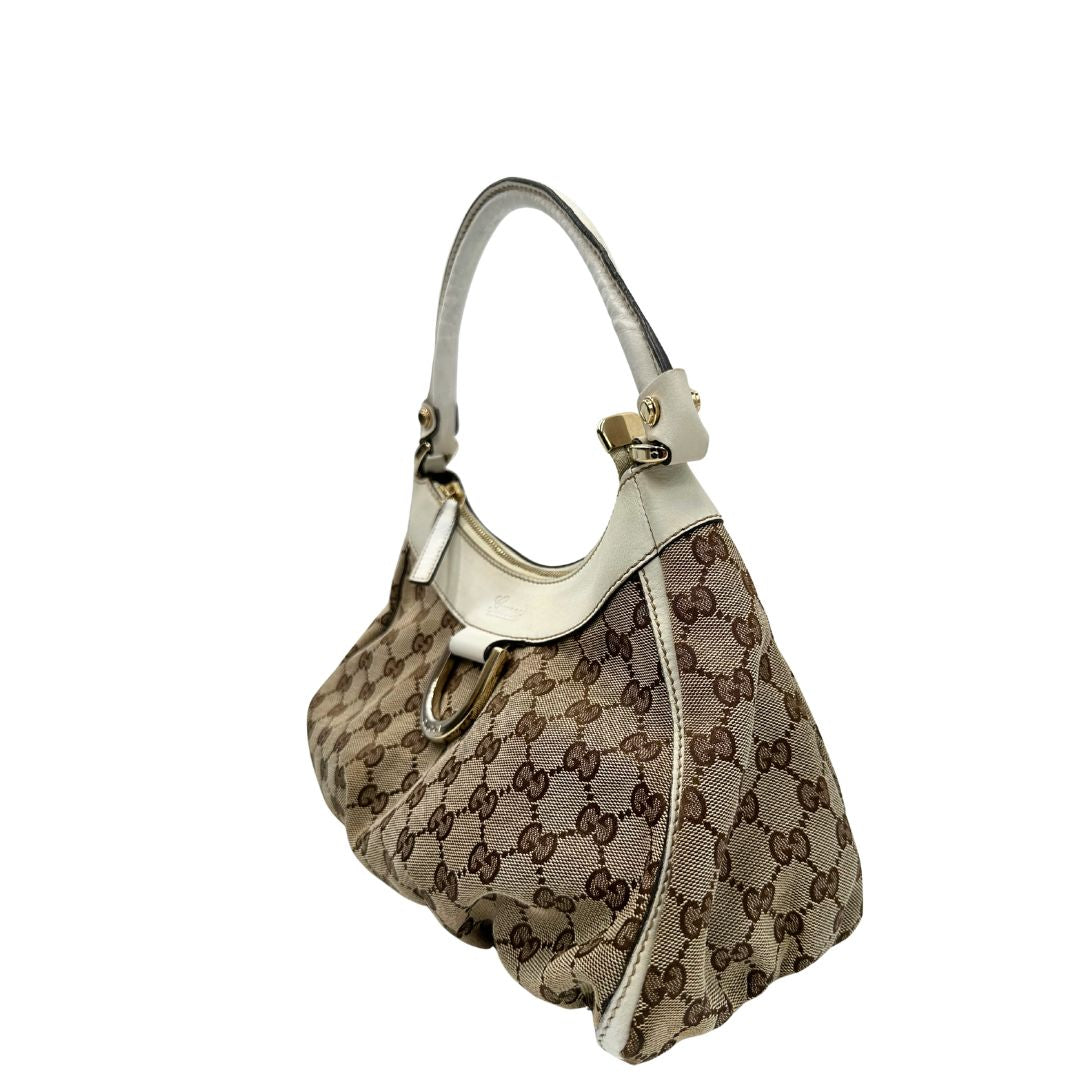 Laterale Borsa Gucci Hobo D-Ring in tessuto beige GG con finiture in pelle bianca e parti metalliche dorate. Munita di un manico in pelle stondato, rifinita con dettaglio D-Ring e logo lettering sul front. Completa di dustbag. Originale, usato, in condizioni ottime. 