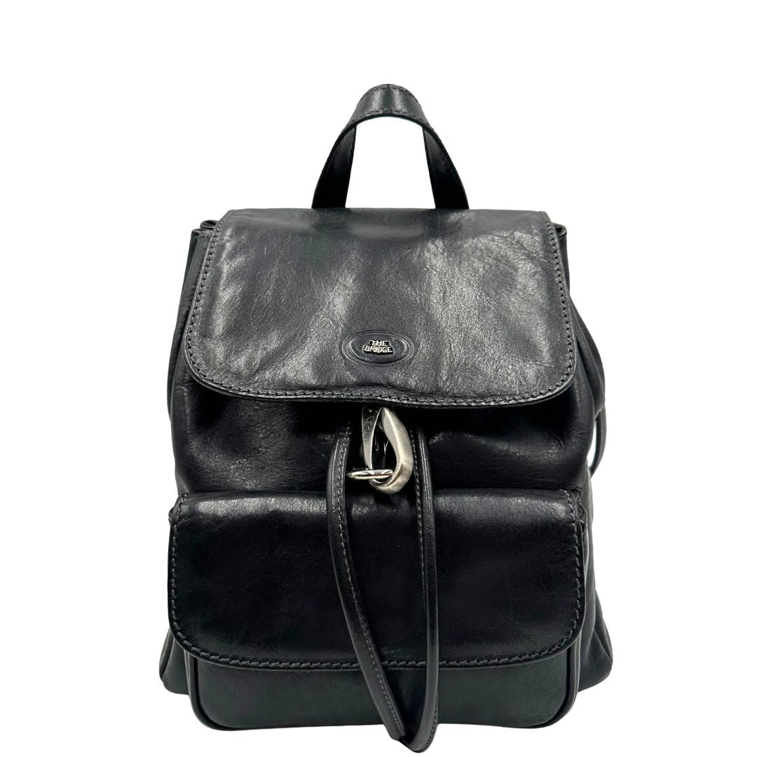 Front di uno zaino The Bridge in cuoio nero con parti metalliche argentate. Cinghie delle bretelle regolabili. Completo di dustbag.