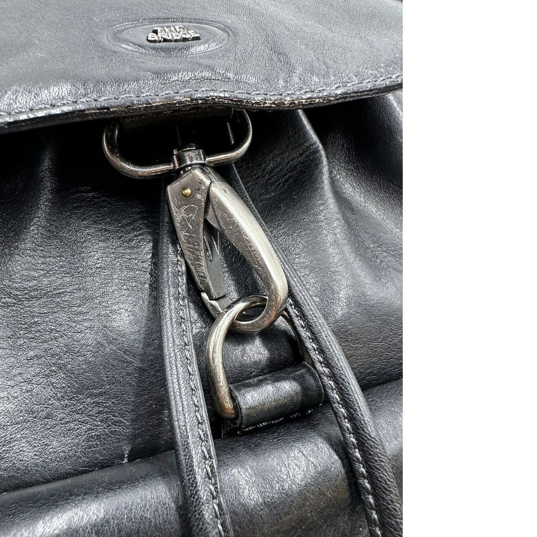 Gancio di chiusura di uno zaino The Bridge in cuoio nero con parti metalliche argentate. Cinghie delle bretelle regolabili. Completo di dustbag.