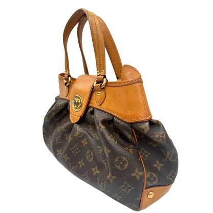 Laterale destro di una borsa Louis Vuitton in canvas marrone monogram con finiture in vacchetta naturale e parti metalliche dorate; munita di doppi manici stondati, da indossare a mano.