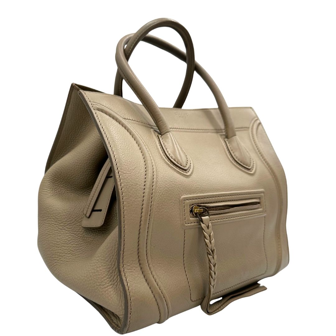 Laterale sinistro di una borsa Céline Luggage in pelle color sabbia con parti metalliche oro anticato ed effetto renio. Completa di dustbag. Indossabile a mano.
