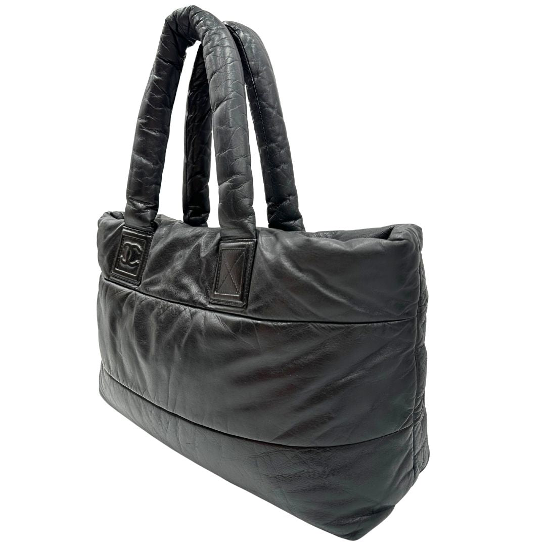 Laterale destro di una borsa Chanel in pelle effetto imbottito nera, con metalleria argentata. Da indossare a spalla.