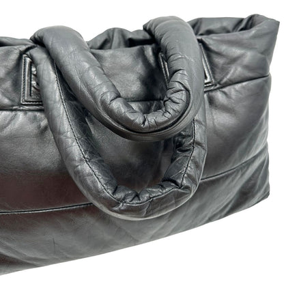 Manici di una borsa Chanel in pelle effetto imbottito nera, con metalleria argentata. Da indossare a spalla.