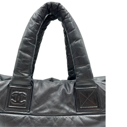 Manici di una borsa Chanel in pelle effetto imbottito nera, con metalleria argentata. Da indossare a spalla.